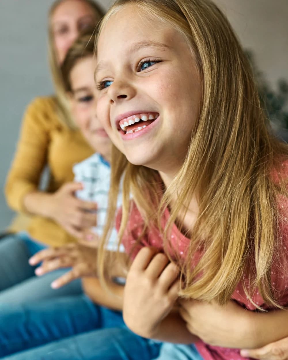A parent and two children sitting together, laughing